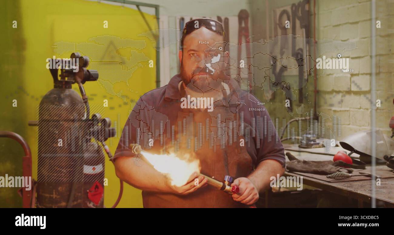 Tenendo in mano la torcia che emette fiamma, il lavoratore indossa grembiule in pelle, occhiali di protezione in officina di metallo, con attrezzi Foto Stock