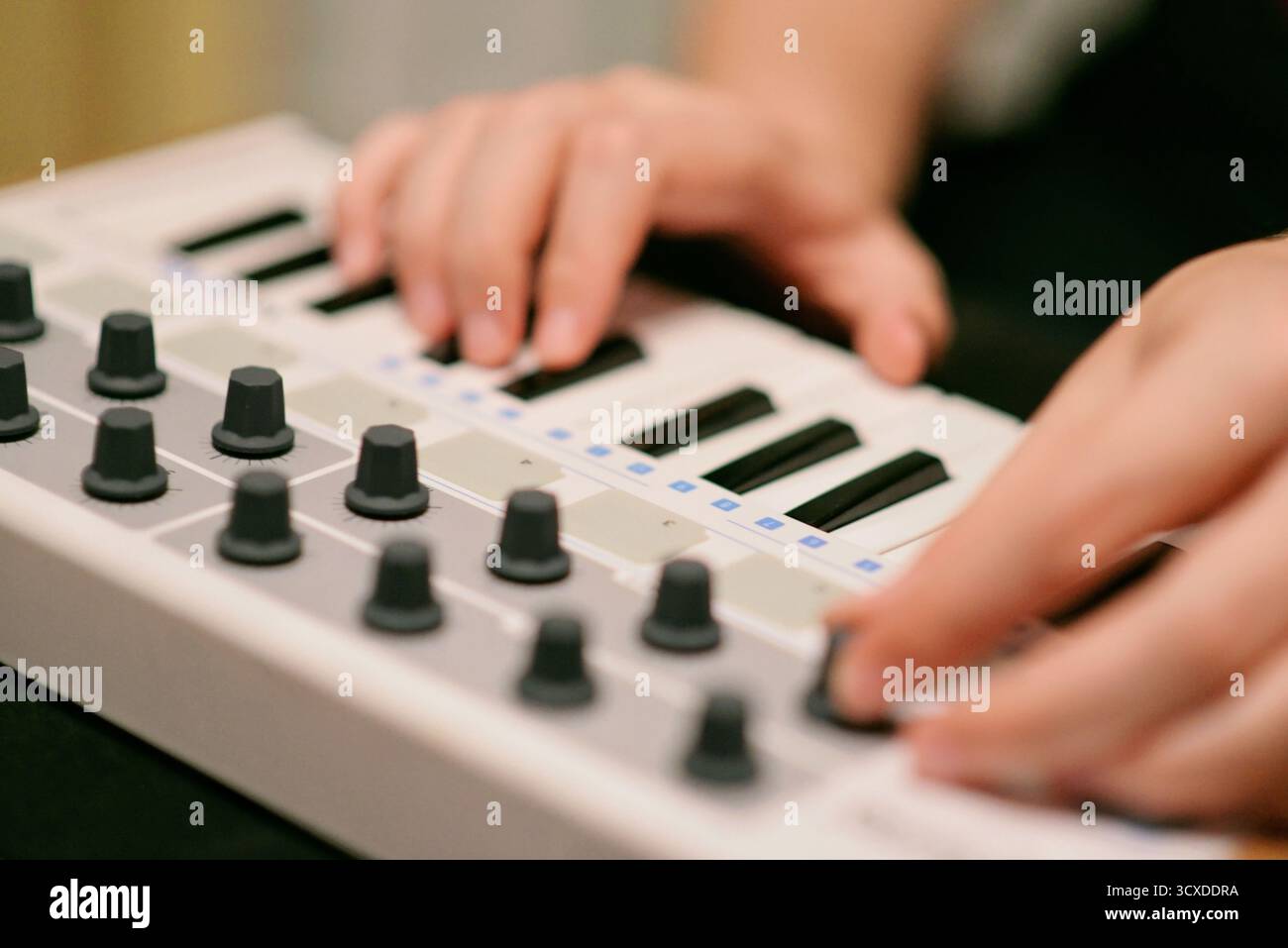Primo piano di un musicista che interagisce con una tastiera sintetizzatore controller MIDI. Produzione di musica elettronica, ideale per i temi del design audio Foto Stock