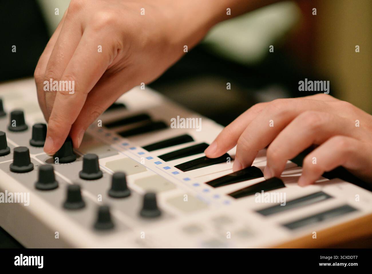 Primo piano di un musicista che interagisce con una tastiera sintetizzatore controller MIDI. Produzione di musica elettronica, ideale per i temi del design audio Foto Stock