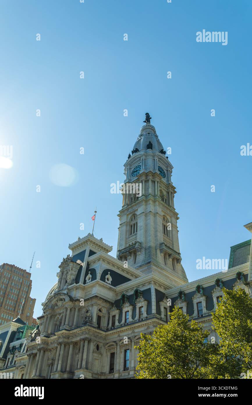 Un municipio di Philadelphia con una torre dell'orologio e una bandiera in cima. Il cielo è limpido e blu Foto Stock Un municipio di Philadelphia con una torre dell'orologio e una bandiera in cima. Il cielo è limpido e blu Foto Stock