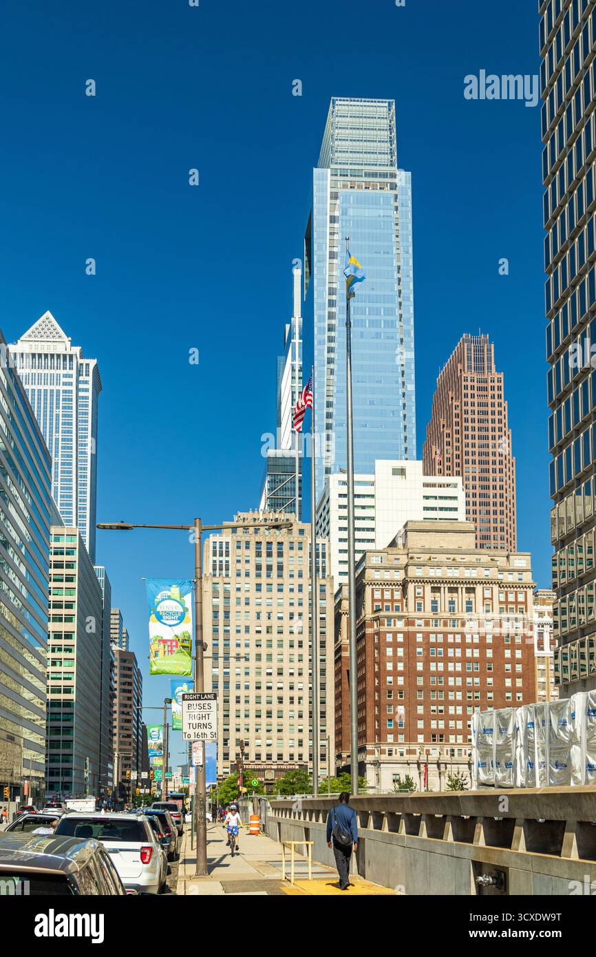 Una strada cittadina con un alto edificio sullo sfondo. Il cielo è blu e il sole splende Foto Stock Una strada cittadina con un alto edificio sullo sfondo. Il cielo è blu e il sole splende Foto Stock