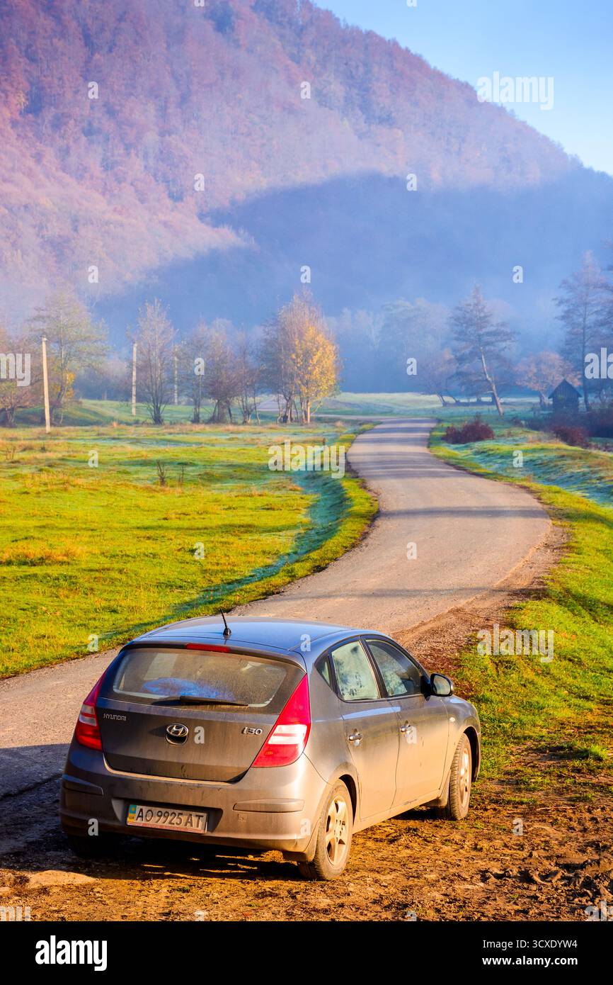 perechyn, ucraina - 10 novembre 2020: auto vicino alla strada asfaltata in autunno. viaggio attraverso il paesaggio di campagna montano dell'ucraina con la nebbia mattutina. cappello hyundai Foto Stock