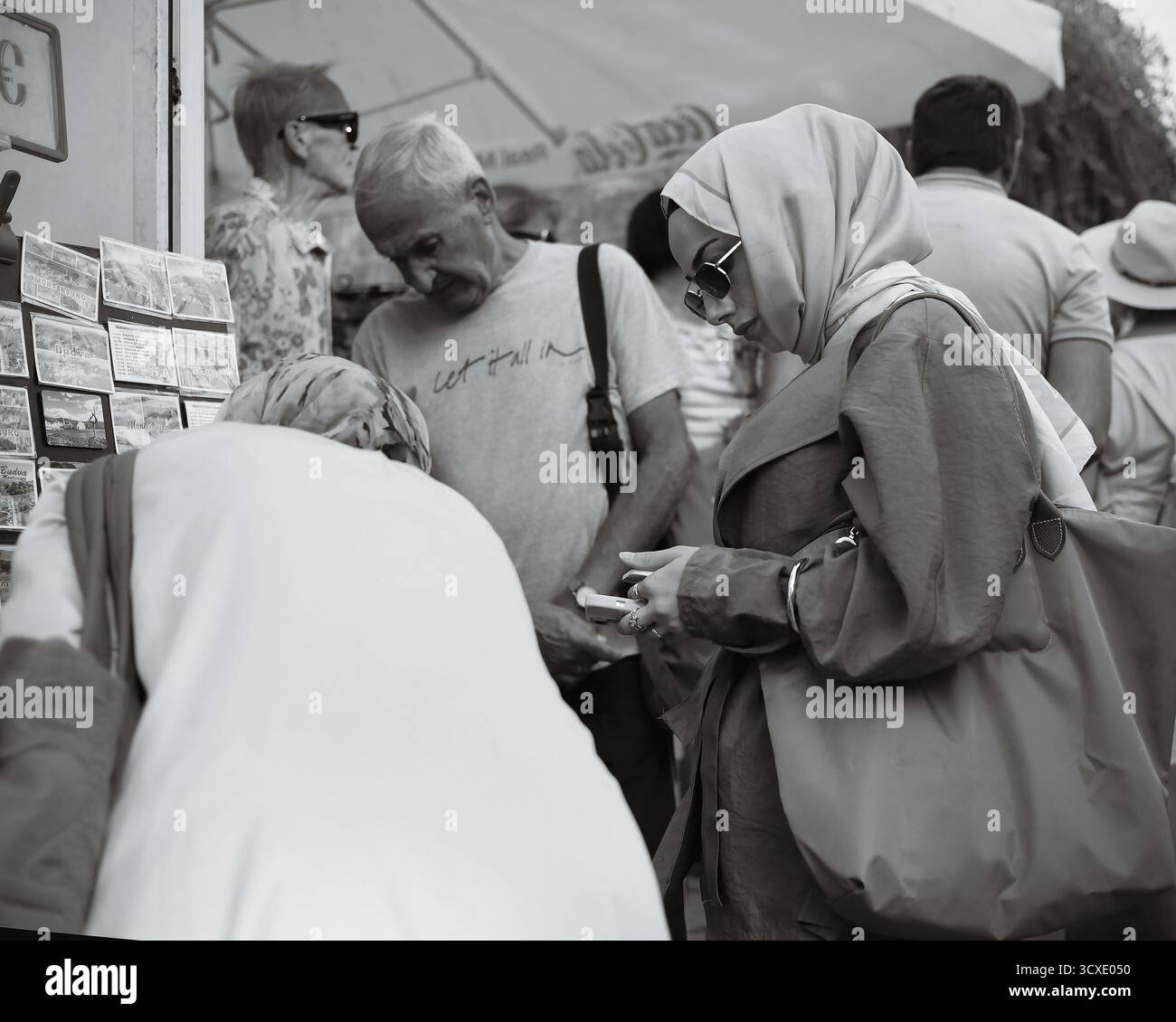 I turisti che navigano nelle cartoline nella città vecchia di Budva, Montenegro, catturati con candide fotografie di strada in bianco e nero. Foto Stock
