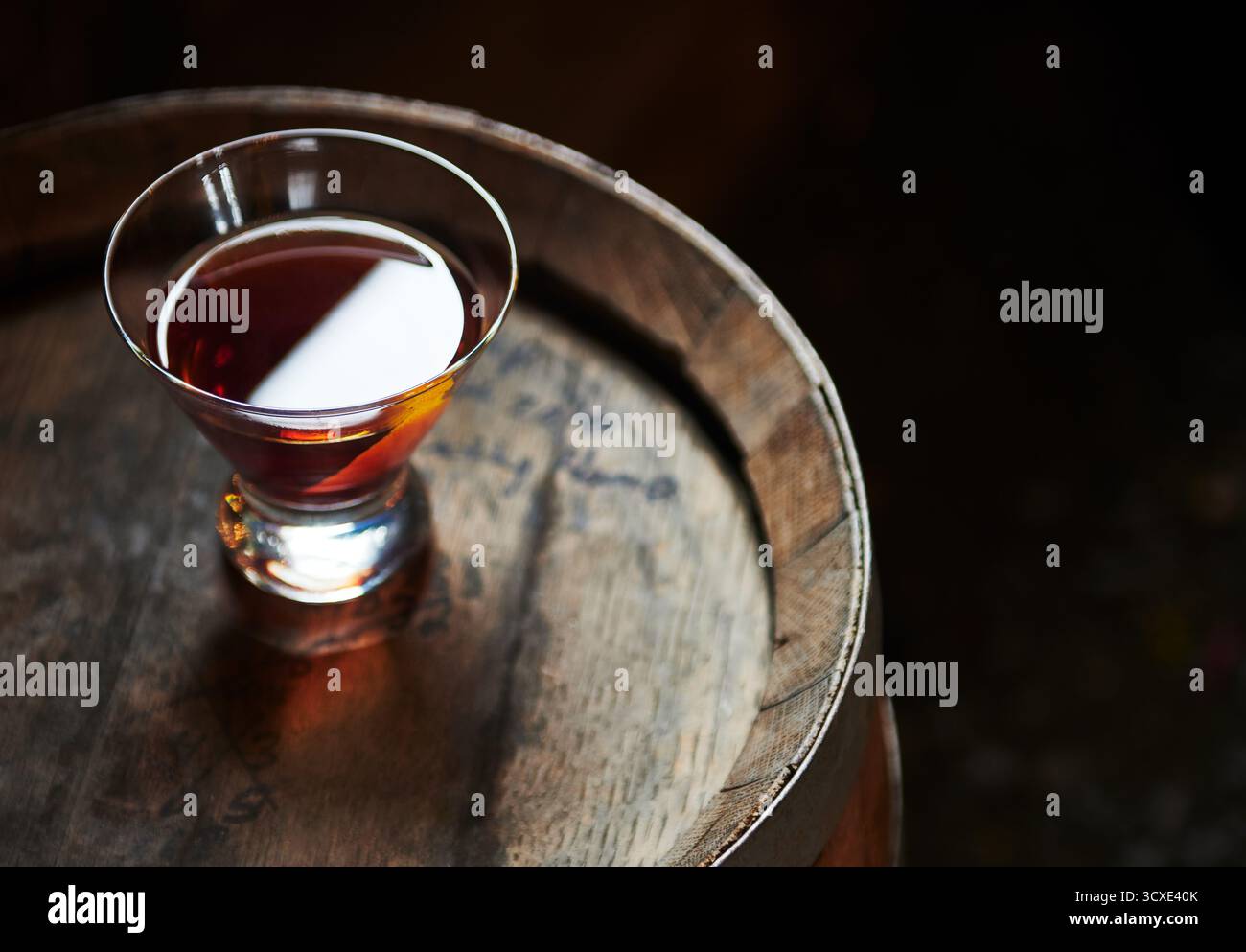 Cocktail di whiskey seduto in cima a un vecchio barile di whisky Foto Stock