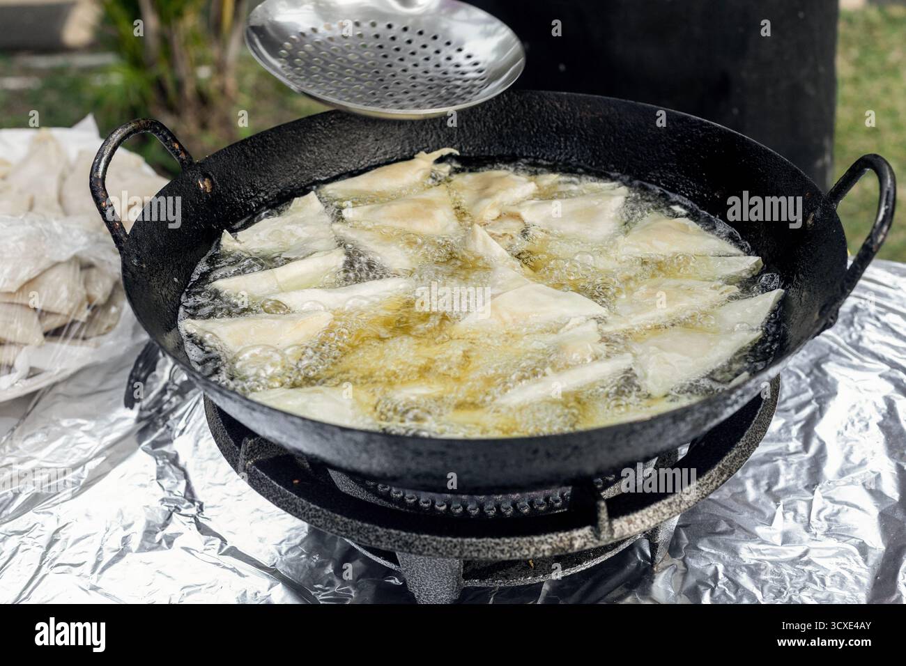 Samosas fritte in olio caldo, un popolare spuntino indiano di Street food Foto Stock