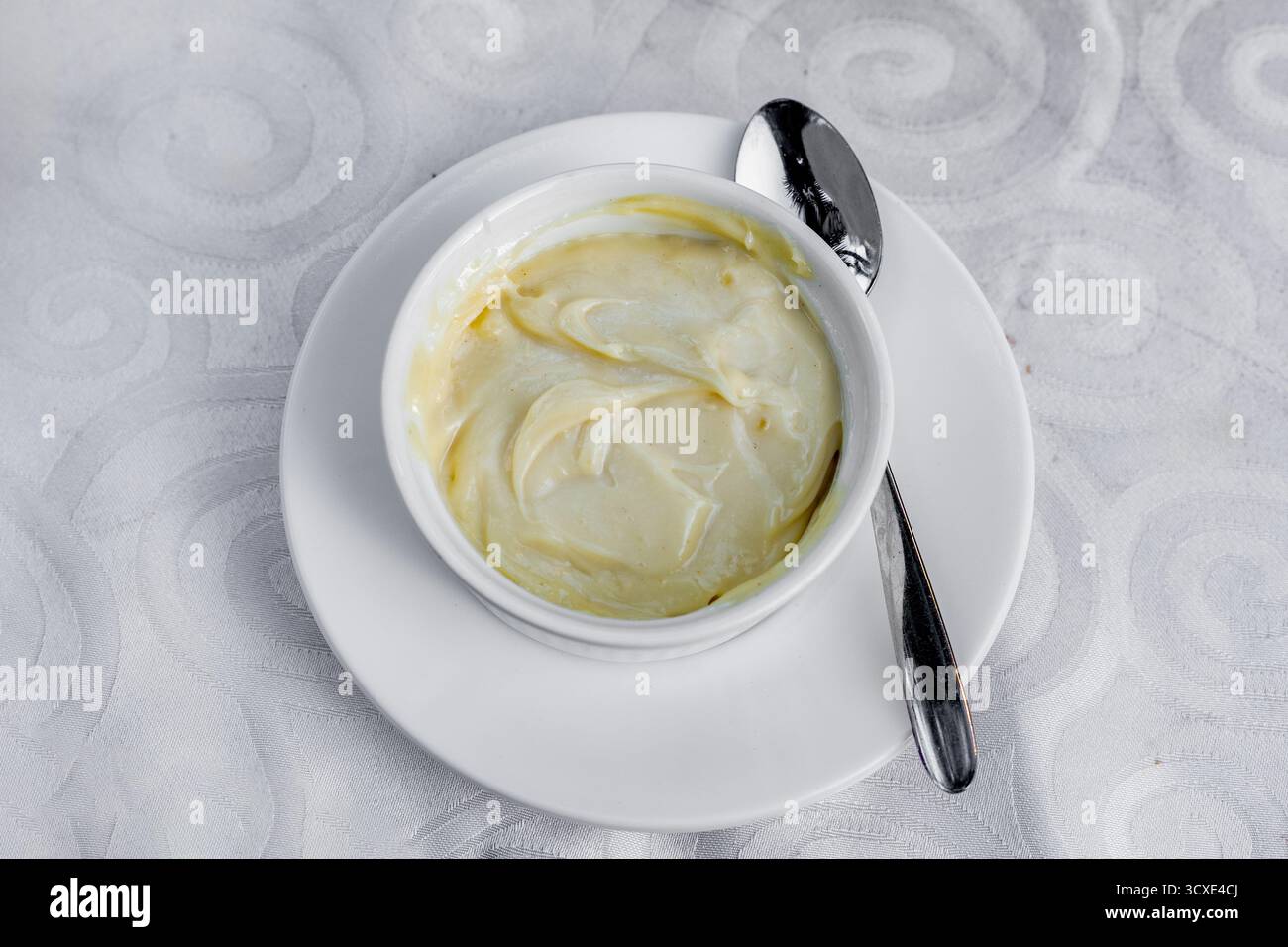 Deliziosa salsa cremosa servita in una piccola ciotola bianca su un piatto bianco Foto Stock