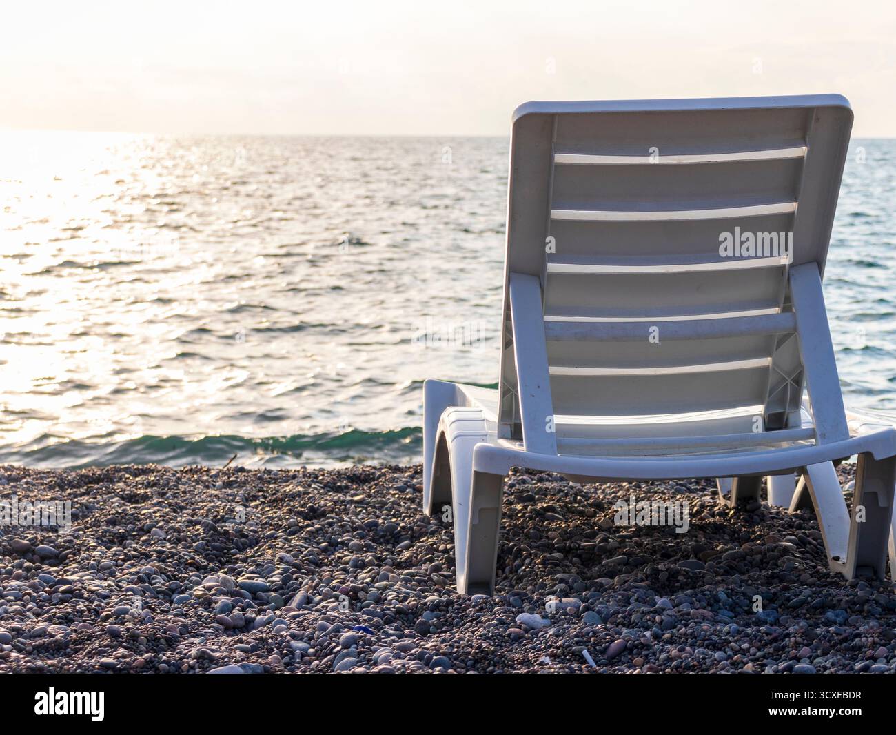 Chaise longue con patio in plastica bianca sulla spiaggia Foto Stock