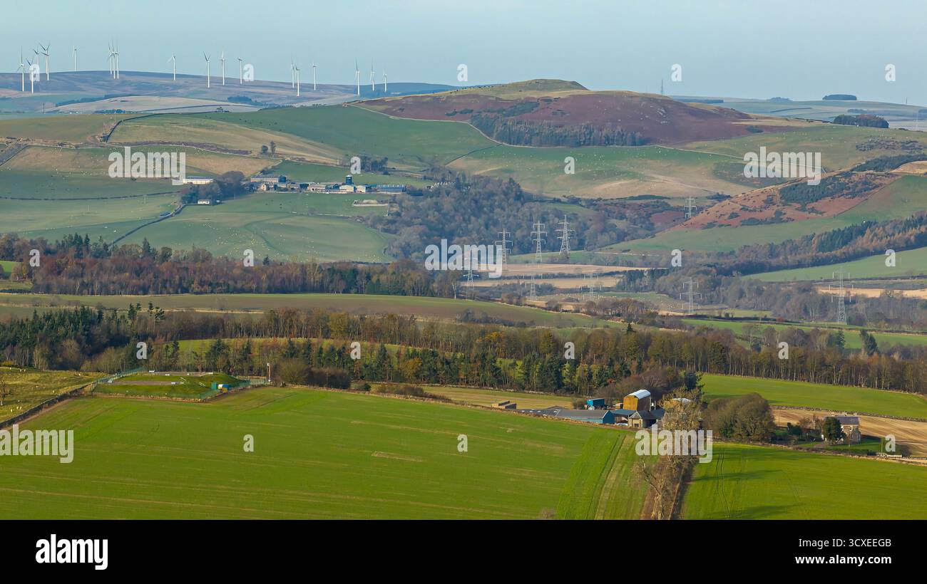 Veduta aerea di terreni agricoli e di una fattoria in funzione vicino a Lauder, Scottish Borders, Scozia, con campi a chiazze, boschi e un traliccio nella luce autunnale Foto Stock