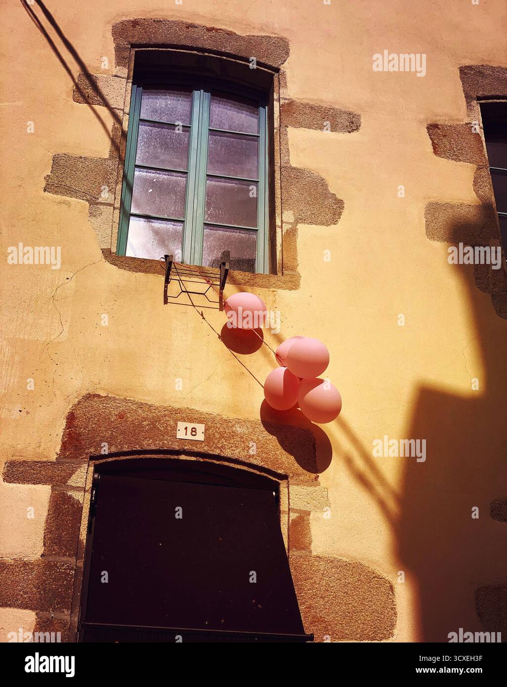 Palloncini rosa appesi da una finestra su una facciata di una vecchia casa Foto Stock