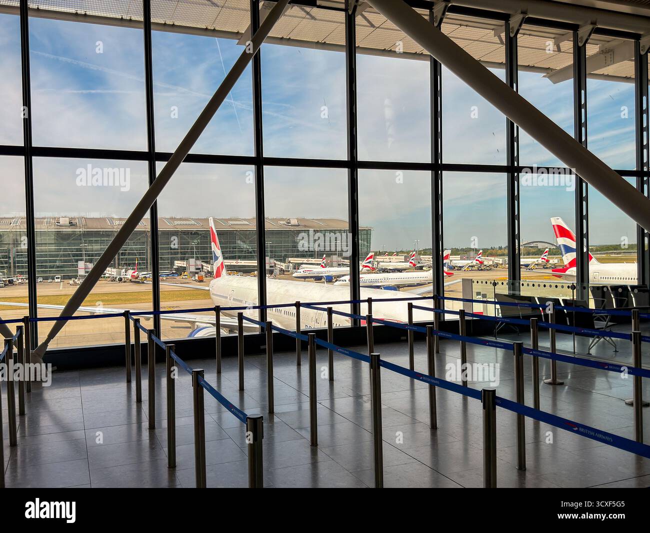Londra, Inghilterra, Regno Unito - 20 maggio 2025: Terminal 5 presso l'aeroporto di Londra Heathrow e gli aerei della British Airways partono dall'interno di uno dei terminali satellitari. - Immagine stock catturata con smartphone