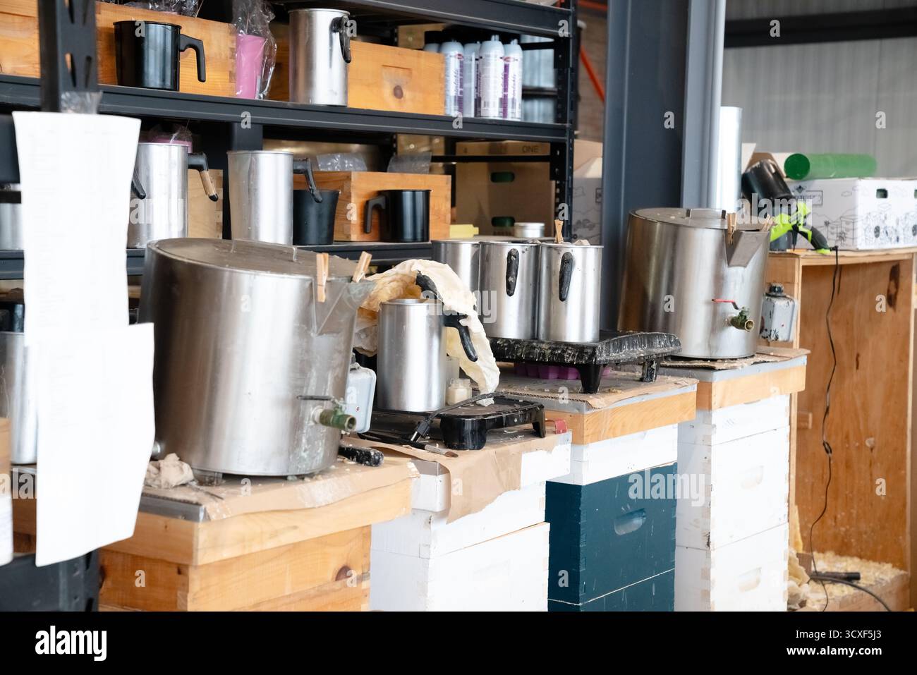 Stazione industriale per la preparazione della cera con vasi di fusione in acciaio inox e contenitori utilizzati per la lavorazione della cera d'api naturale in un'officina di apicoltura Foto Stock