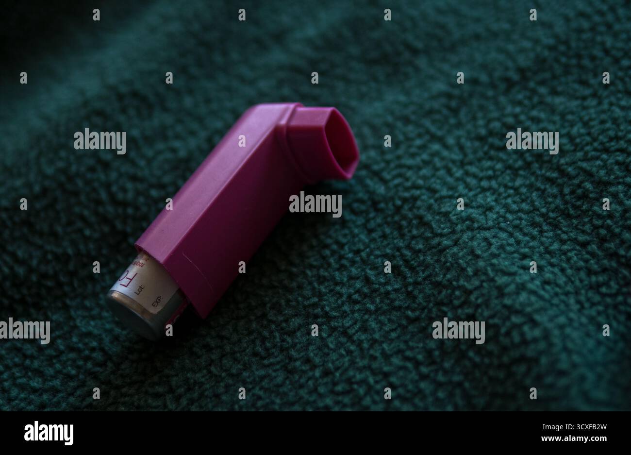 Inalatore per asma viola su sfondo in tessuto verde Foto Stock