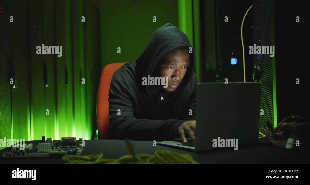 Tecnico addetto ai collaudi che ripara la scheda madre in sala server con laptop e cavi di rete Foto Stock