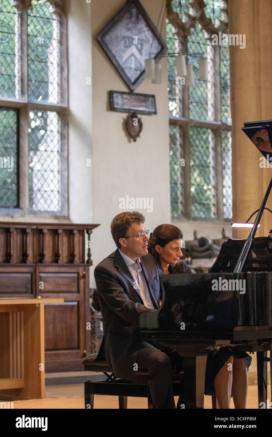 La coppia Emma Abbate e Julian Perkins si esibiscono a St Michael's Church Framlingham in un concerto pomeridiano di metà settimana di duetti per pianoforte su un pianoforte a coda Foto Stock