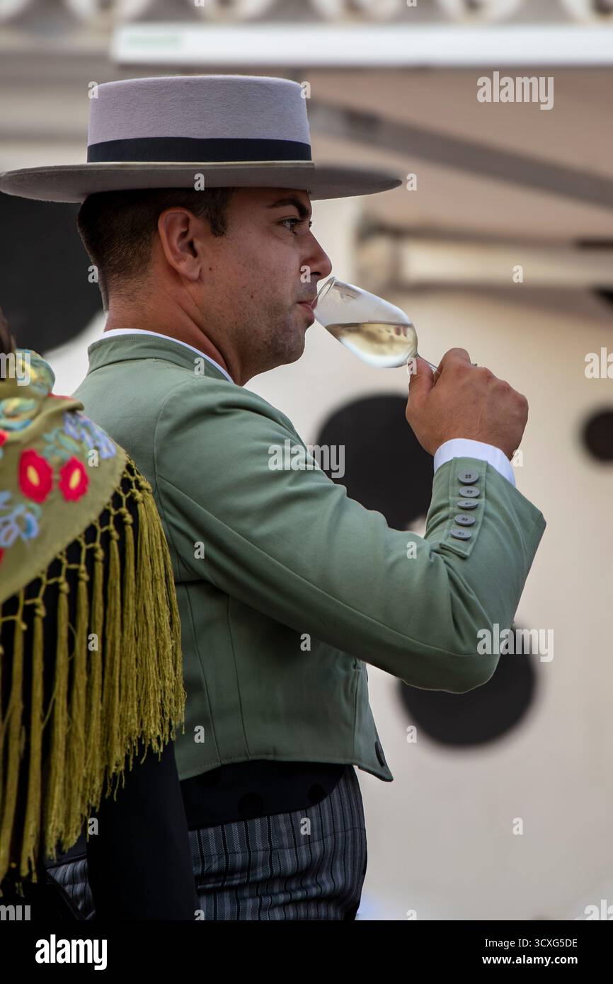 Fuengirola, Málaga, Spagna. 12 ottobre 2025. Uomo che indossa il tradizionale costume da cavaliere andaluso che beve vino spagnolo durante l'ottobre di Fuengirola Foto Stock