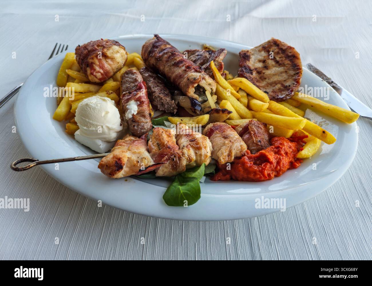Un grill misto che comprende patatine fritte, hamburger, salsiccia, maiale e kebab Foto Stock