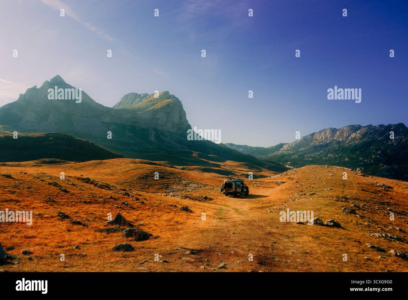 Pulmino fuoristrada parcheggiato in una valle di montagna dorata sotto un cielo blu cristallino nel Parco Nazionale del Durmitor, in Montenegro Foto Stock