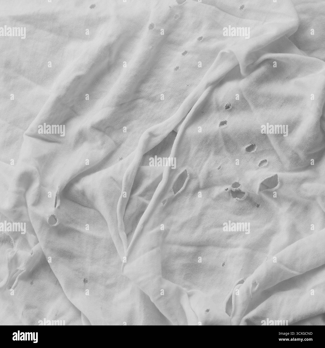 Una t-shirt usurata con fori. Bianco e nero. Primo piano. Foto Stock