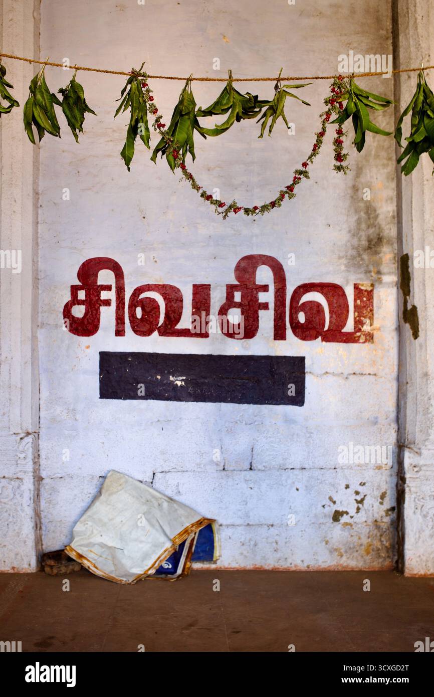 Iscrizione murale con la scritta "Siva Siva" in lingua tamil con ghirlande sopra, all'interno del tempio di Arulmigu Jambukeswarar, Tiruchirappalli, Tamil Nadu, India. Foto Stock