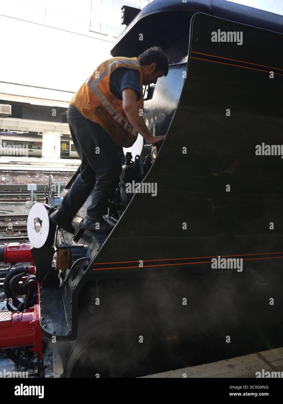 Macchinista di locomotiva a vapore in gilet ad alta visibilità con motore per treni storici Foto Stock