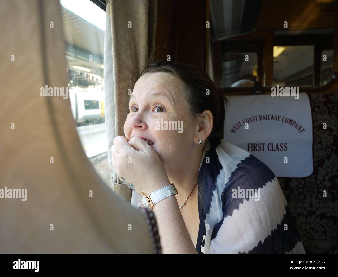 Donna che guarda fuori dal finestrino in carrozza ferroviaria di prima classe sul treno della West Coast Railway Company Foto Stock Donna che guarda fuori dal finestrino in carrozza ferroviaria di prima classe sul treno della West Coast Railway Company Foto Stock