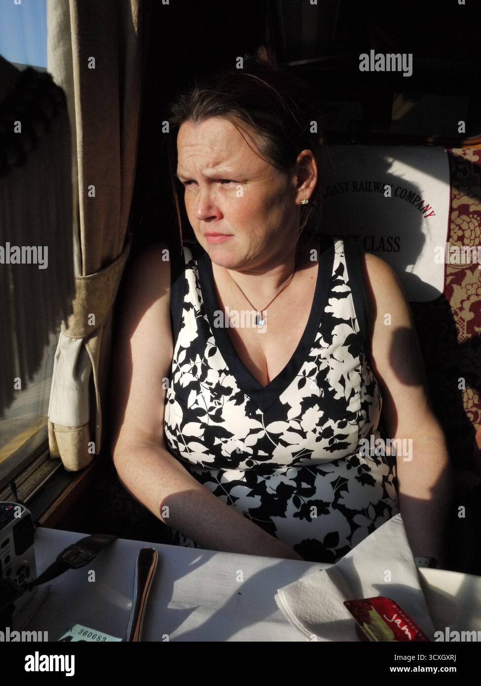 Passeggero donna su una carrozza ferroviaria a vapore d'epoca alla luce del sole Foto Stock
