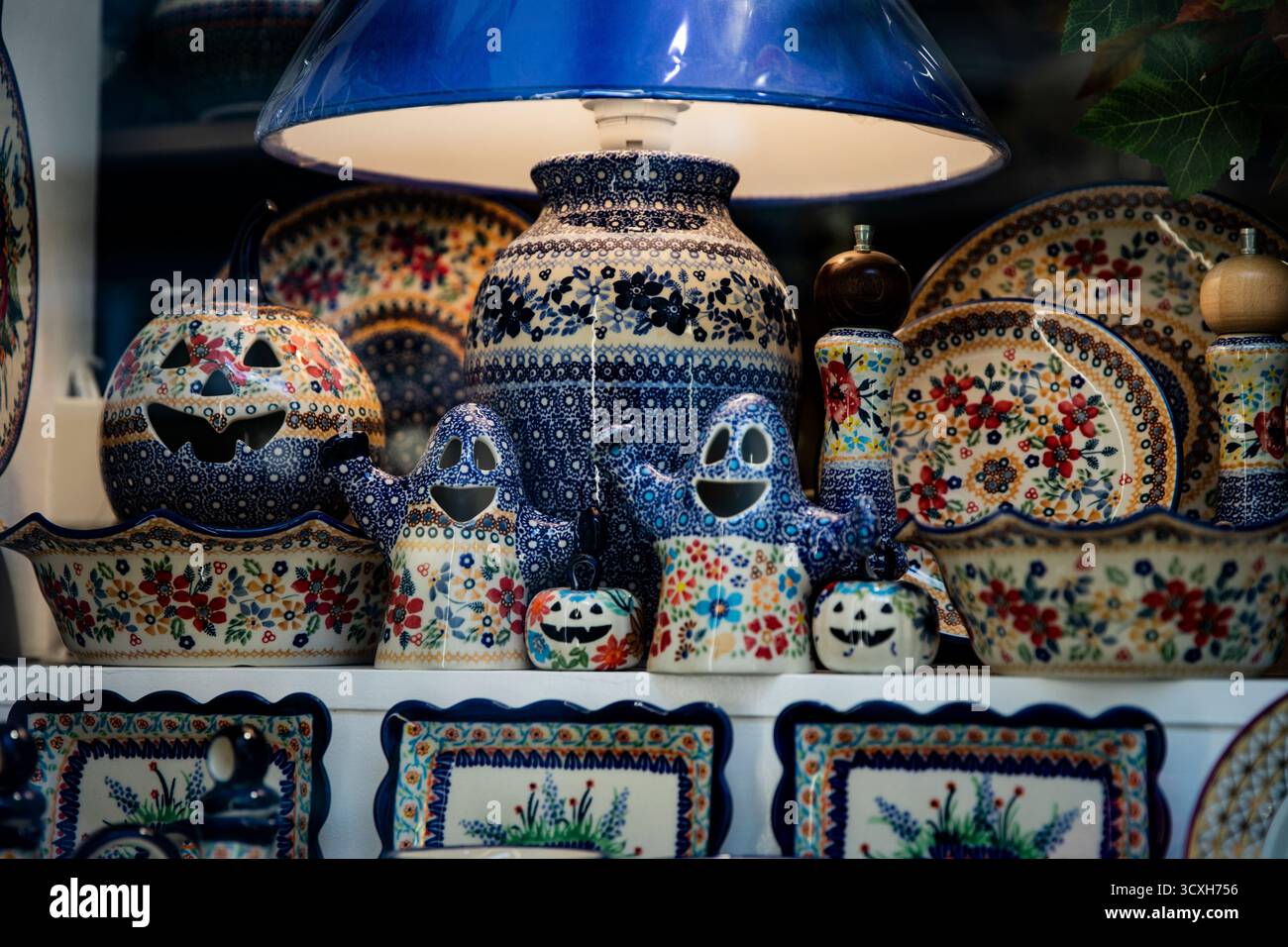 Ceramica artigianale polacca tradizionale e arte ceramica splendidamente sistemata in vetrina decorata a Natale. Lampada e condimenti con pompelmo Foto Stock