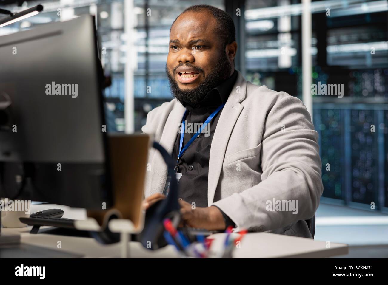 Programmatore spaventato nella sala server preso dal panico da un rapporto diagnostico che mostra un malfunzionamento hardware critico sul PC. Un lavoratore afroamericano spaventato disturbato da notifiche di errore che rischiano l'uptime del sistema Foto Stock