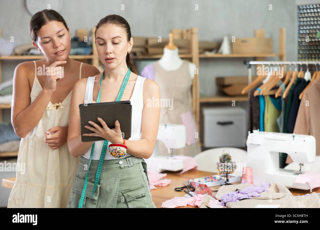 Due sarte che disegnano un modello di vestiti su un tablet Foto Stock