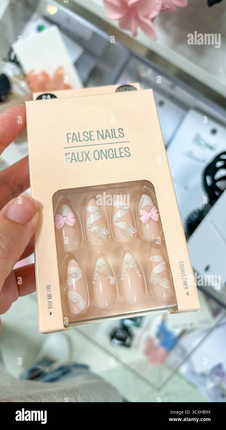Ottawa ON, Canada - 16 agosto 2025: Scatola di unghie false tenute in mano, che mostra un design elegante con archi rosa e motivi floreali nel negozio di bellezza Foto Stock