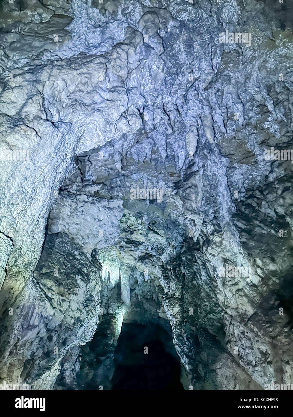 Impressionanti stalattiti e tessuti calcarei all'interno della Grotta di ghiaccio nel canyon di Uvac, Serbia, illuminati da luce naturale e artificiale. - Immagine stock catturata con smartphone