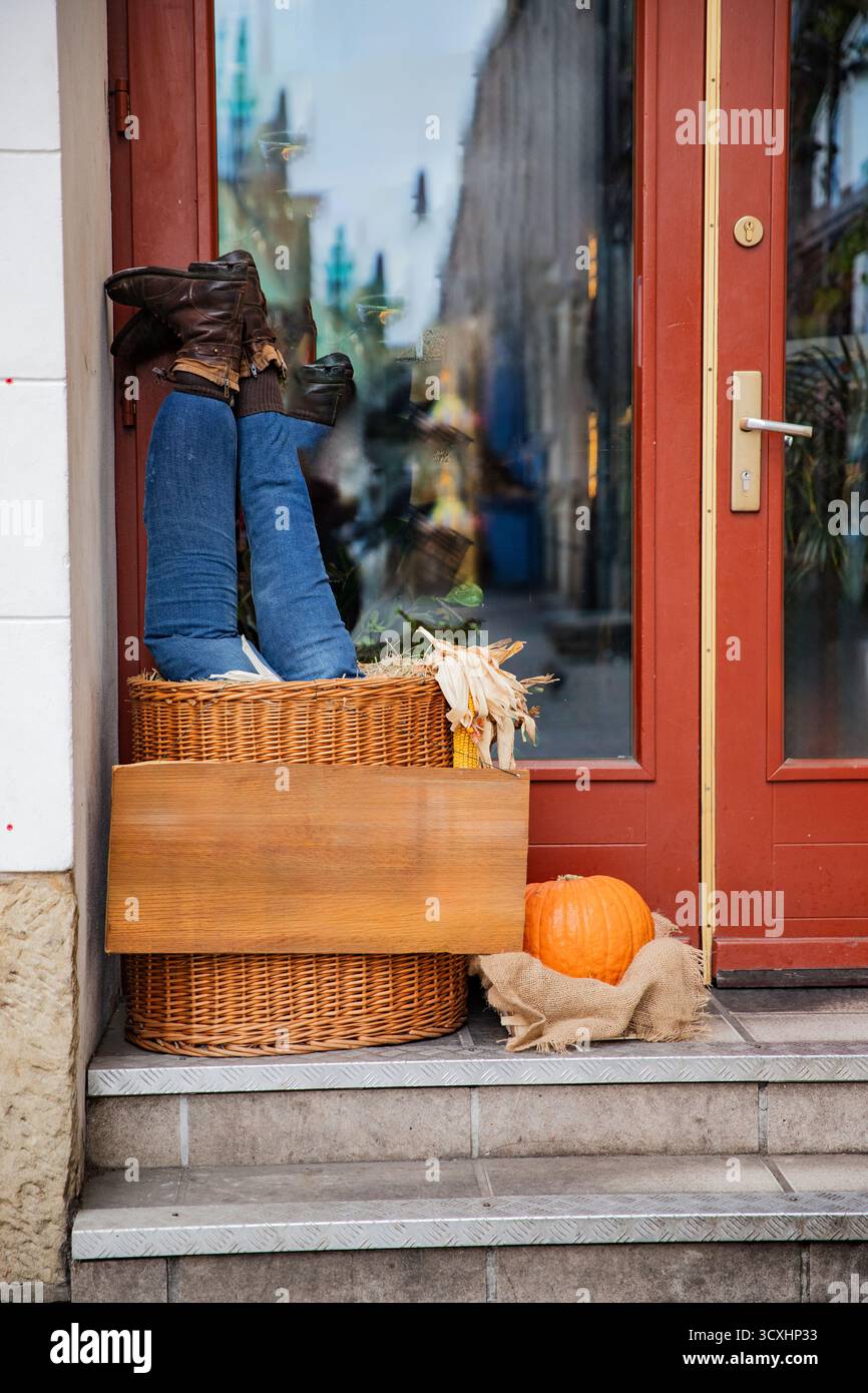 Decorazioni in stile umoristico con portico autunnale con jeans e stivali capovolti sui gradini. Preparatevi per Halloween Foto Stock