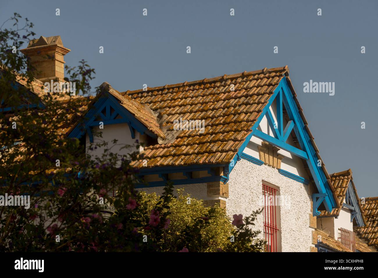 Tipica casa inglese nel quartiere Reina Victoria di Huelva, con un tetto spiovente con piastrelle marroni, legno blu, finestre rosse e un camino. Foto Stock