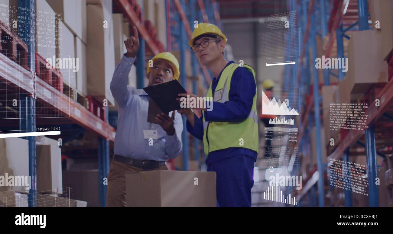 Due lavoratori che indossano caschi e giubbotti per la revisione delle scorte nei corridoi del magazzino, con portadocumenti e scatole Foto Stock