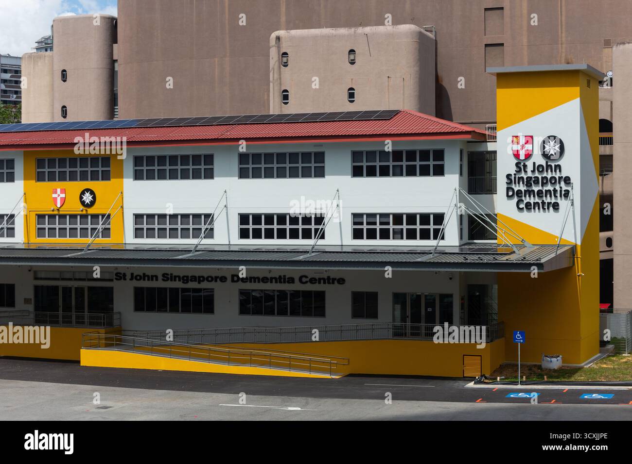 Design architettonico del St John Singapore Dementia Centre. Design della rampa per sedia a rotelle. Grande logo e cartellonistica sull'edificio. Aspetto pulito. Foto Stock