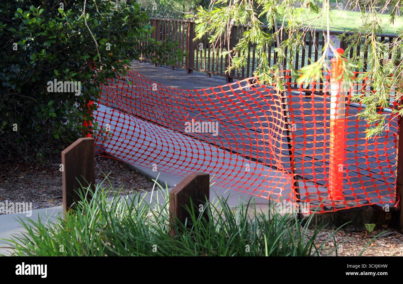 Rete di sicurezza che circonda un molo di legno in un parco con piante Foto Stock