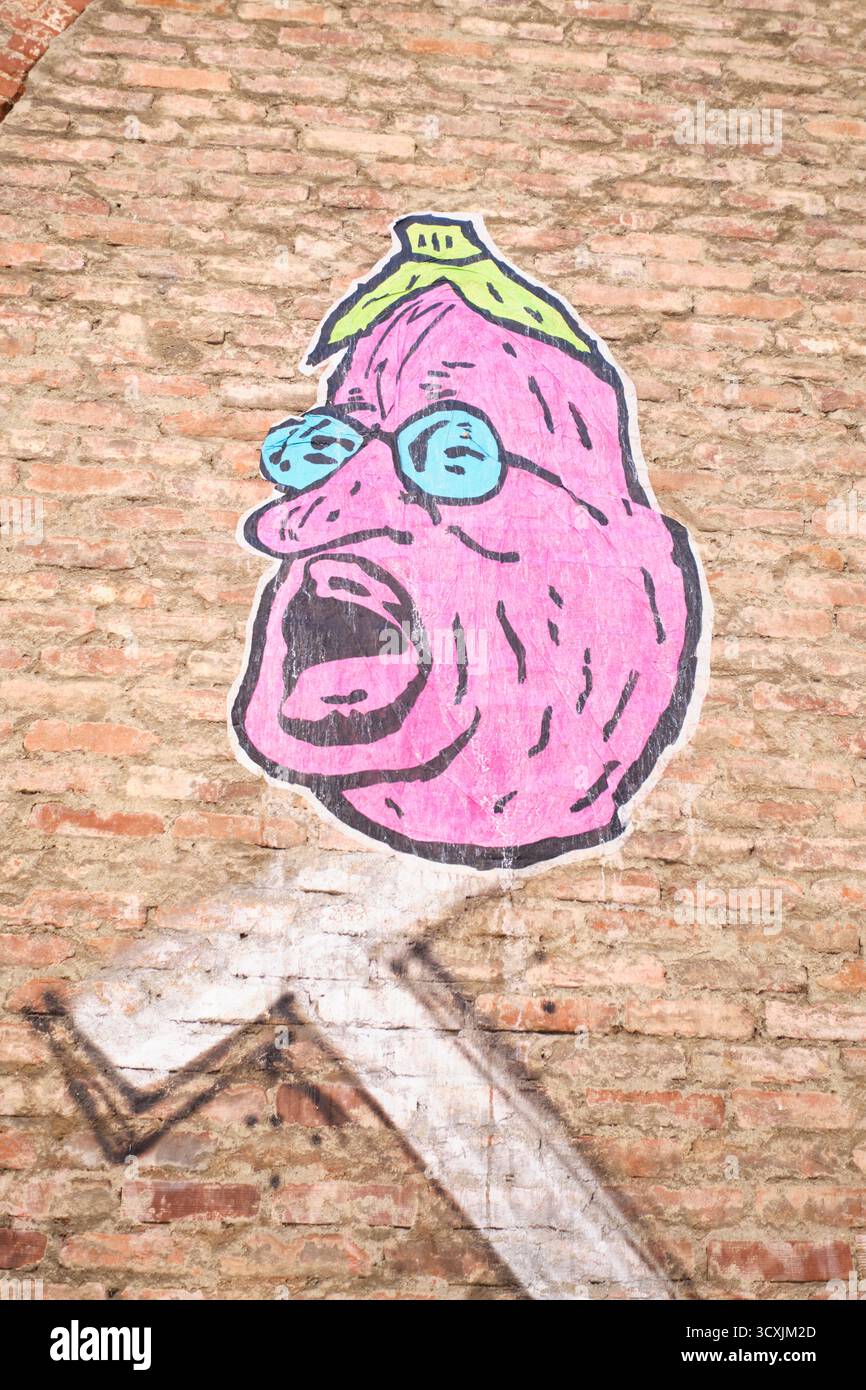 Uno stencil di graffiti, adesivo di una melanzana cartoni animati che è la testa di un uomo, viso con naso e occhiali grandi. divertente, sciocco, stupido. A Torino, Torino, Italia. Foto Stock