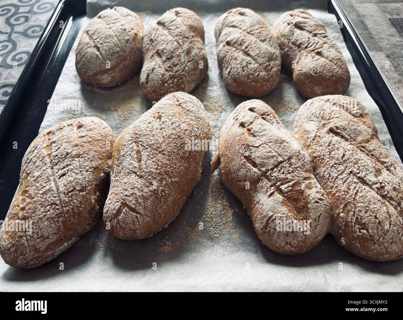 Panini appena sfornati. Mini baguette di pane fatte in casa, perfette per sandwich o colazione. Concetto di cottura in casa. Foto Stock
