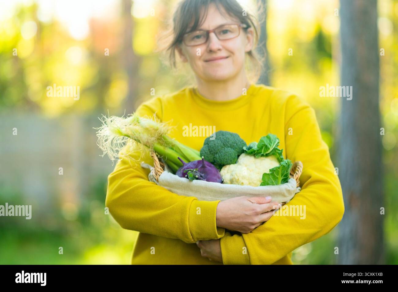 Ritratto di donna contadina sorridente con cesto di broccoli, cavolfiore, cavolfiore e mais. Raccolta di verdure autunnali, prodotti agricoli, cibo sano, stile di vita agronomo, dieta biologica ricca di fibre. Foto Stock