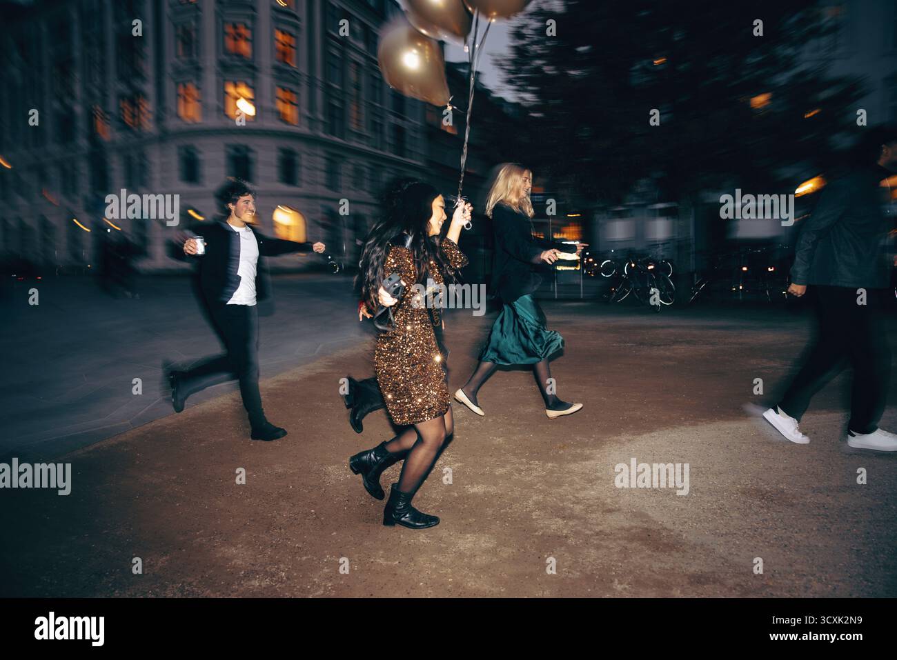 Un gruppo gioioso di amici che si godono una serata avventurosa all'aperto con una vibrante energia. Attraversano un ambiente urbano sotto luci accese, radi Foto Stock