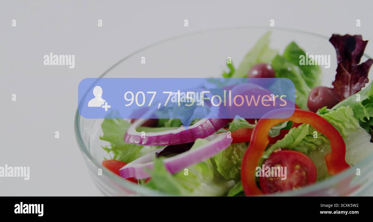 Mostra la ciotola di insalata in vetro con gli ingredienti in studio, con una bolla blu che mostra 907.715 follower Foto Stock