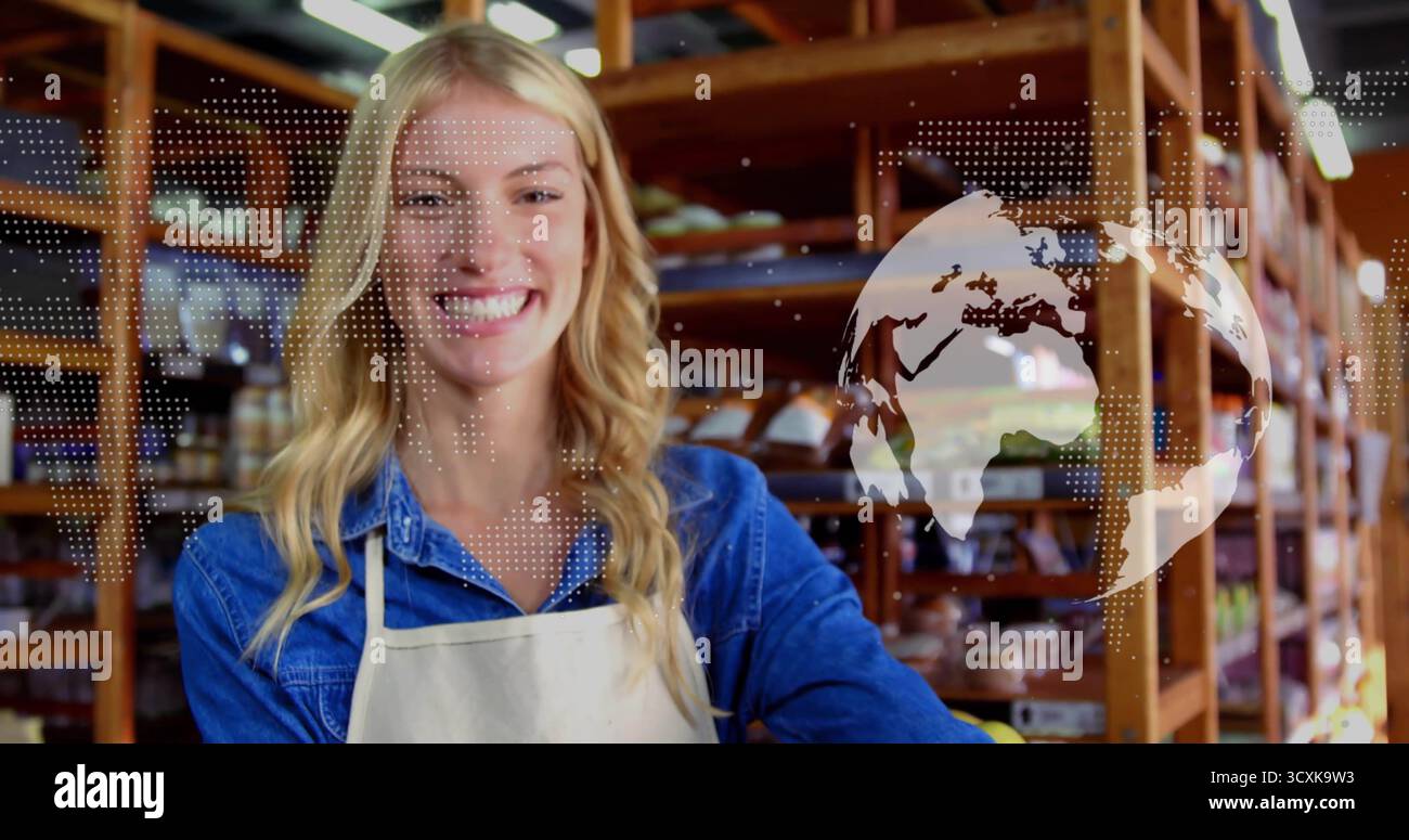 Donna adulta sorridente che indossa un grembiule che prepara il pane sugli scaffali all'interno della panetteria con sovrapposizione della mappa del mondo Foto Stock