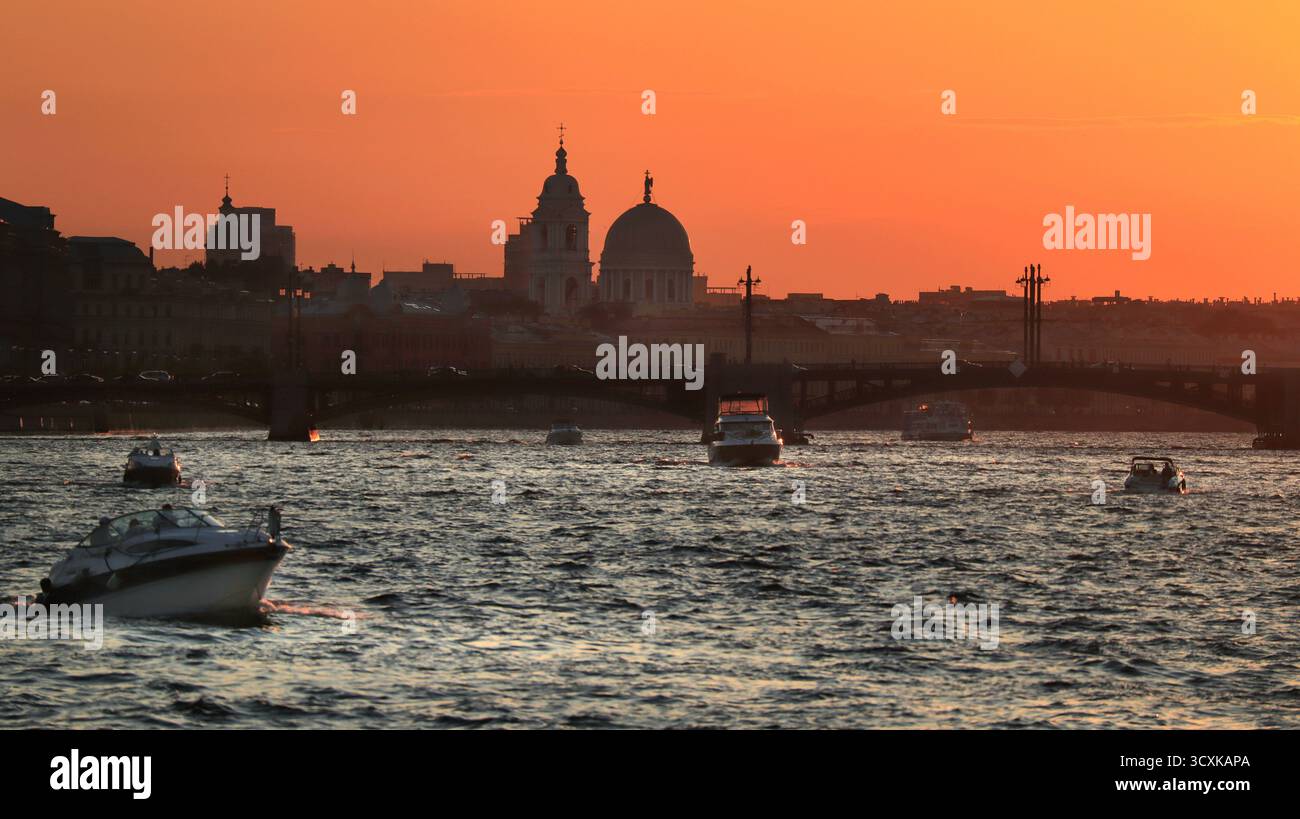 Vista del fiume Neva con alcuni yacht a vela e profilo della città di San Pietroburgo sotto il cielo rosso del tramonto Foto Stock