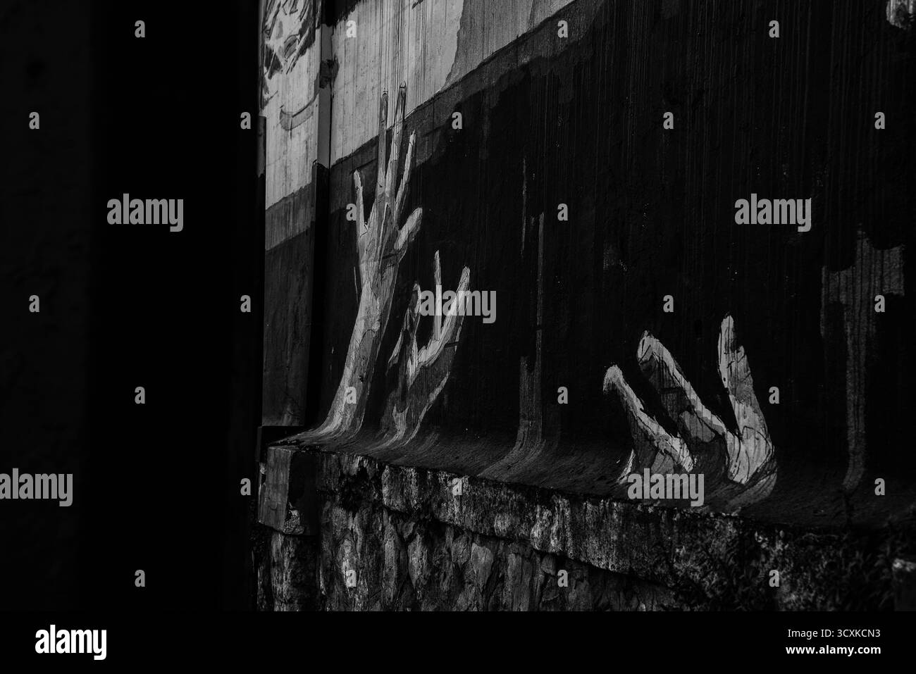 Street art in bianco e nero raffigurante mani dipinte su un muro. Foto Stock