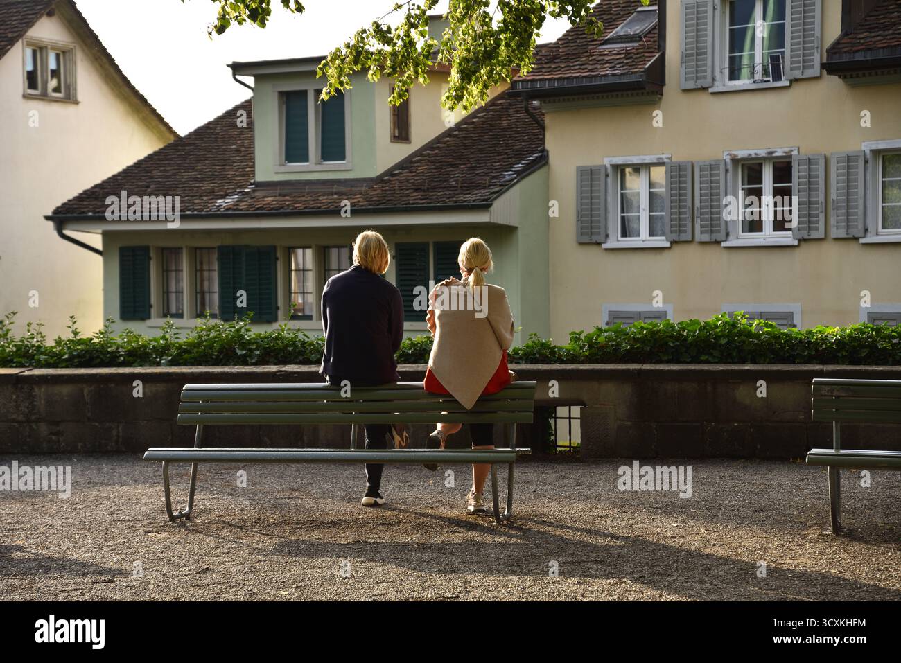 Una coppia seduta di fronte a case tradizionali in un punto panoramico di Lindenhof a Zurigo, Svizzera Foto Stock