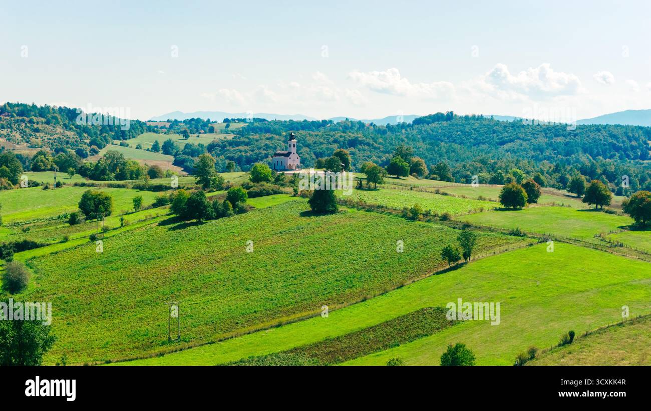 Vista droni della piccola chiesa ortodossa circondata da campi e colline Foto Stock