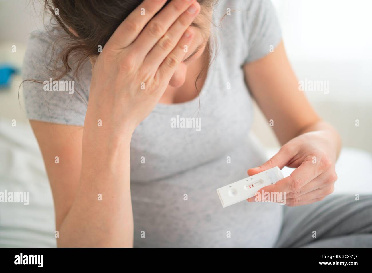 Aspettarsi che la madre visualizzi ansiosamente i risultati dei test PCR a casa. Diagnostica avanzata per le malattie infettive durante il periodo di gravidanza sensibile. Foto Stock