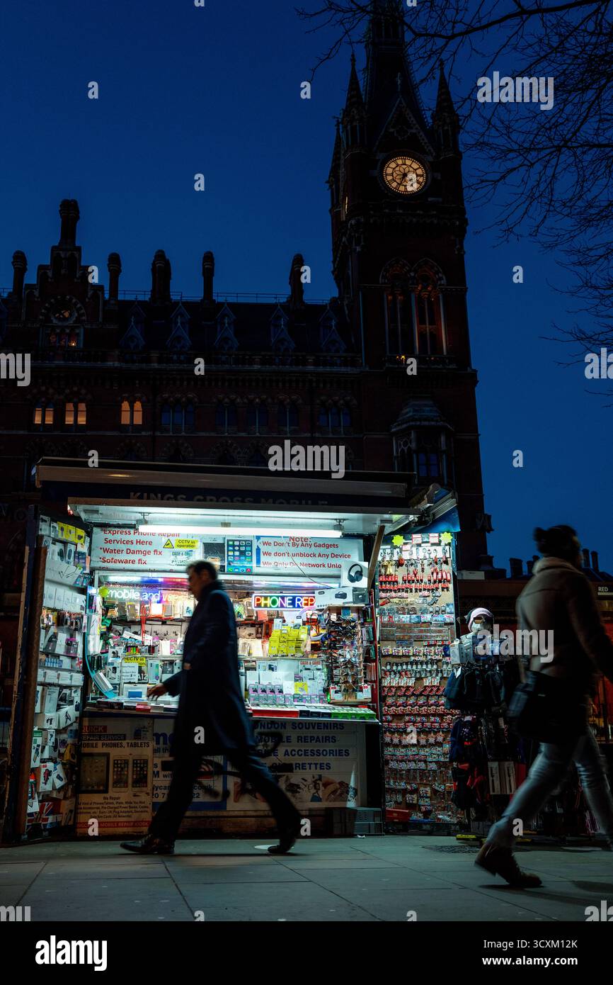 Chiosco stradale illuminato sotto la torre dell'orologio di St Pancras, scatto notturno a Londra Foto Stock