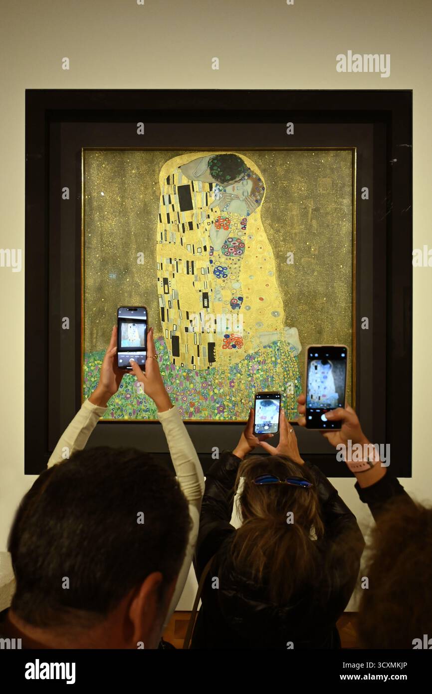 Vienna, Austria - 12 ottobre 2025: Turisti con smartphone che fotografano il famoso dipinto il bacio di Gustav Klimt nella galleria del Belvedere, in verticale Foto Stock