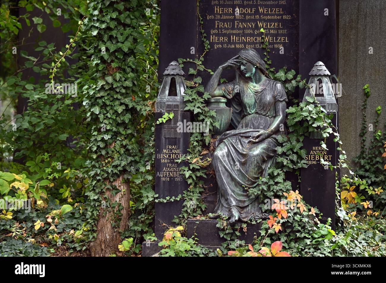 Monumento storico con statua malinconica intemprata circondata da edera e lapidi nel cimitero centrale di Vienna (Zentralfriedhof) Foto Stock